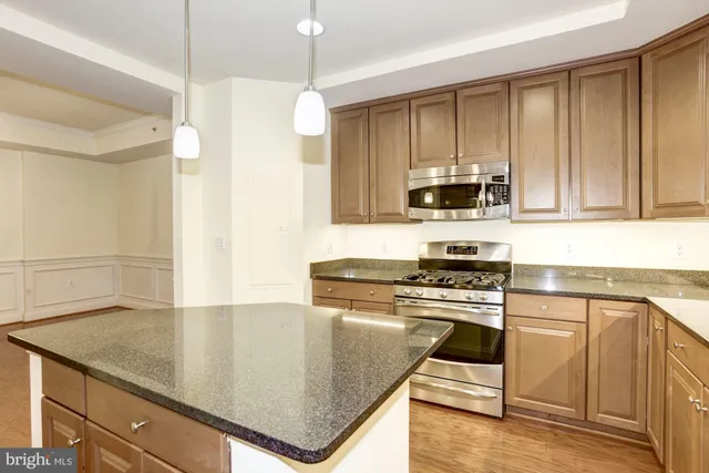 a kitchen with granite countertop a stove a sink and a refrigerator