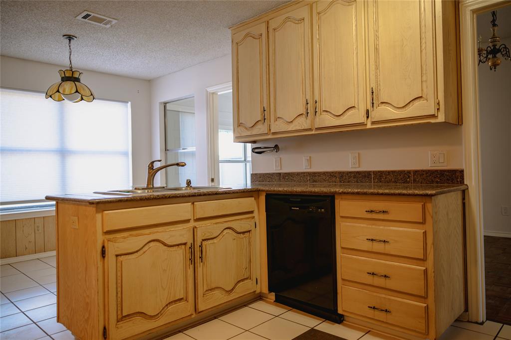 9029 Church Road Dallas, TX 75231 - Photo 15 of 40 a kitchen with stainless steel appliances granite countertop a sink and dishwasher a refrigerator with wooden cabinets
