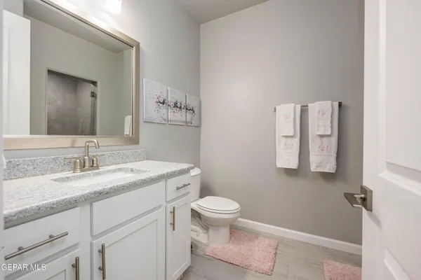 a bathroom with a granite countertop sink toilet and mirror