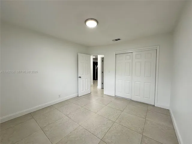 an empty room with a white cabinet and a window