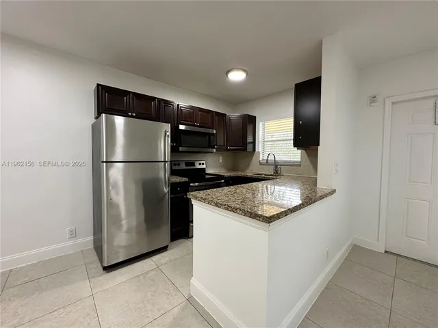 a kitchen with stainless steel appliances granite countertop a refrigerator a sink and a stove