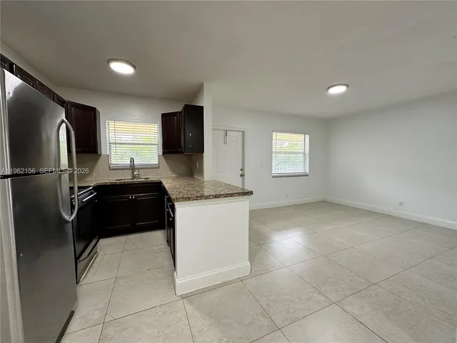 a kitchen with granite countertop a refrigerator and a stove top oven