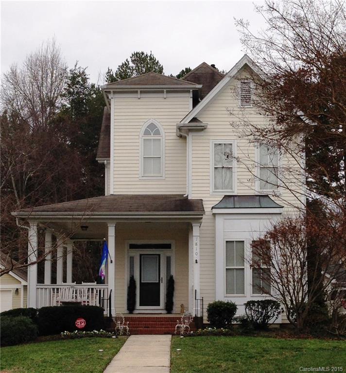 a view of a white house with a large windows and a yard with plants and large trees