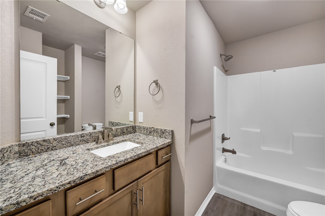 1218 High Street Navasota, TX 77868 - Photo 12 of 16 a bathroom with a granite countertop sink a mirror a toilet and bathtub