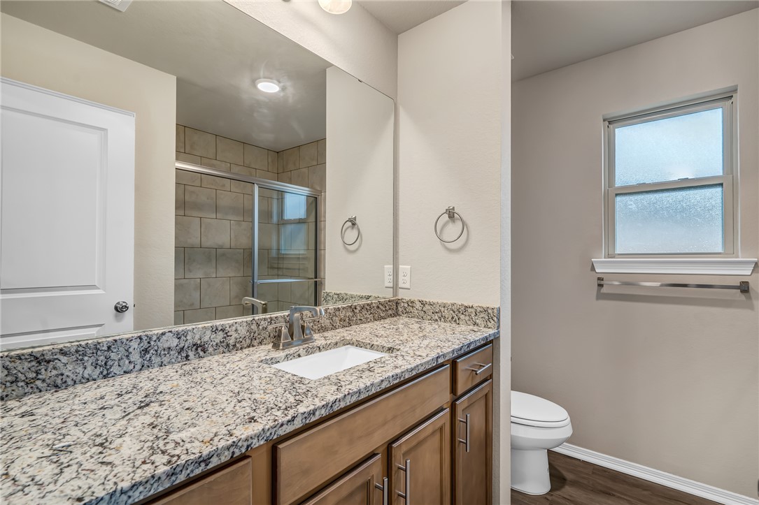 1218 High Street Navasota, TX 77868 - Photo 10 of 16 a bathroom with a granite countertop sink a toilet and a mirror