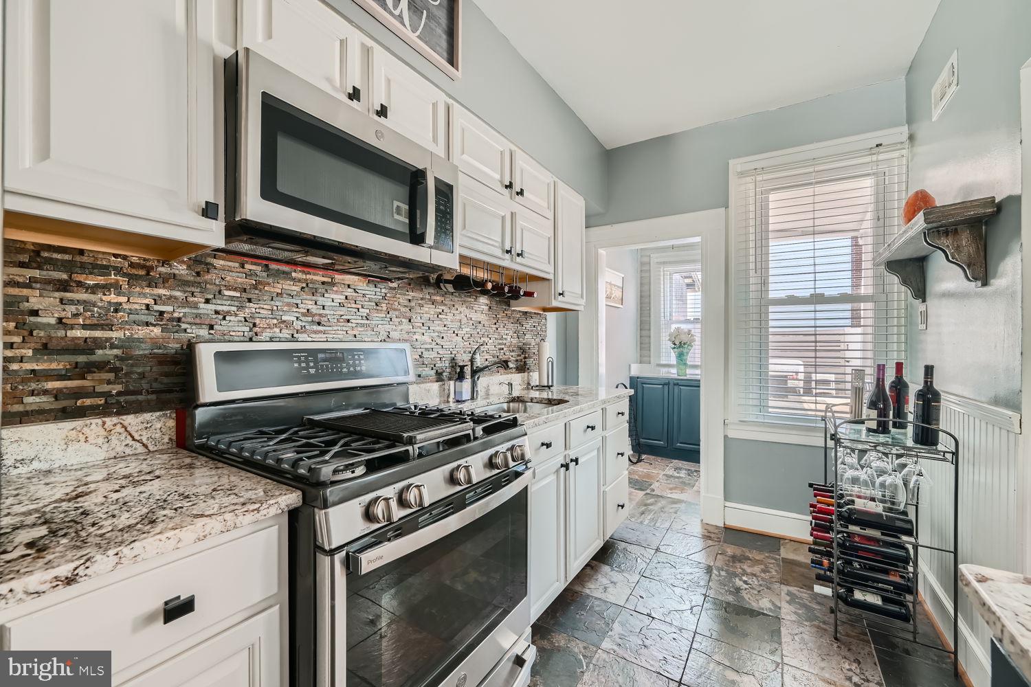 1215 West Old Cold Spring Lane Baltimore, MD 21211 - Photo 13 of 33 a kitchen with stainless steel appliances granite countertop a stove microwave and cabinets