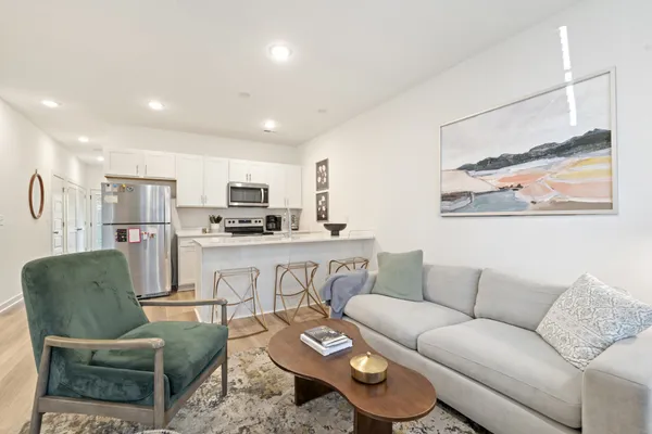 a living room with furniture kitchen view and a window