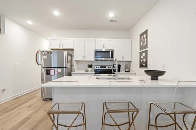 a kitchen with stainless steel appliances a refrigerator sink and white cabinets