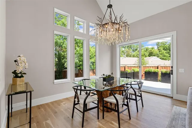 a view of a dining room with furniture a chandelier and large windows