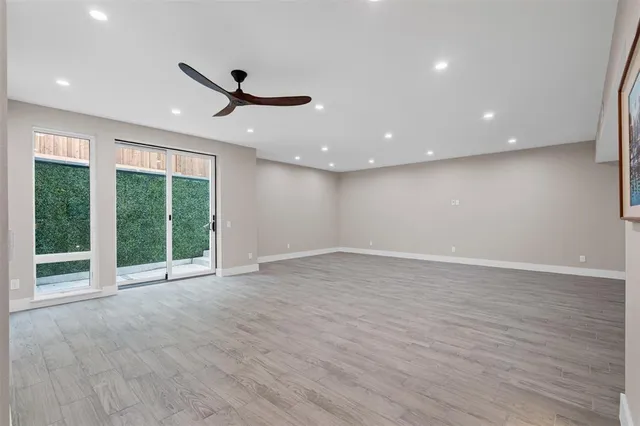 a view of an empty room with wooden floor and windows