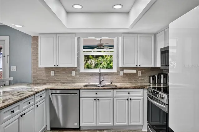a kitchen with white cabinets and window