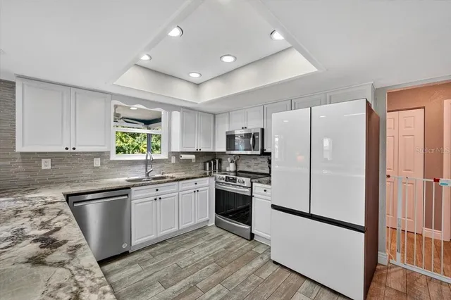 a kitchen with stainless steel appliances granite countertop a refrigerator sink and stove