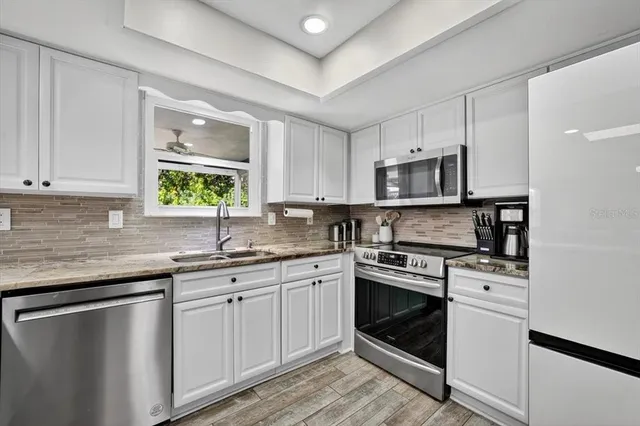 a kitchen with stainless steel appliances granite countertop a stove sink and cabinets