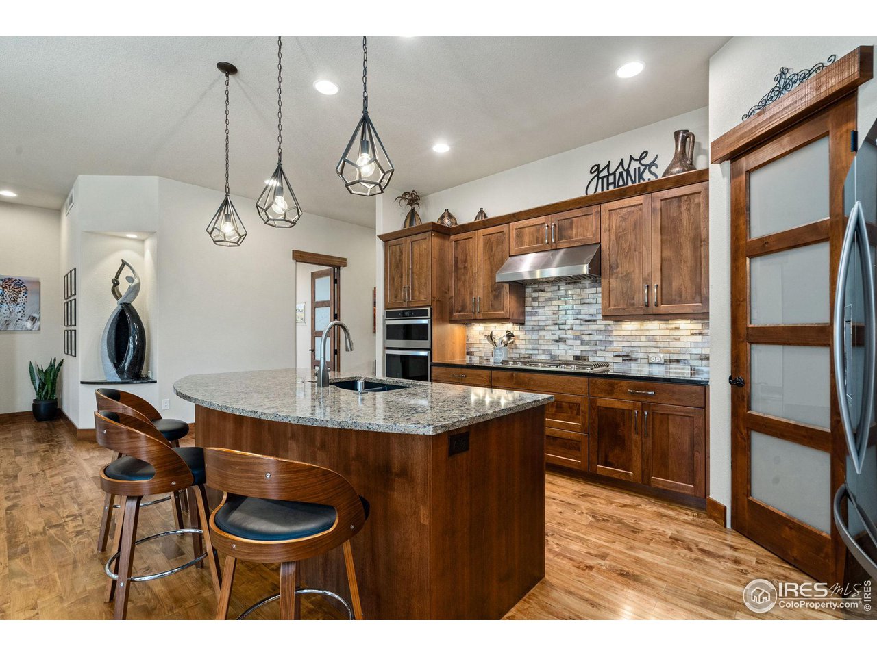 6611 Murano Drive Windsor, CO 80550 - Photo 4 of 35 a kitchen with kitchen island granite countertop a sink cabinets and stainless steel appliances