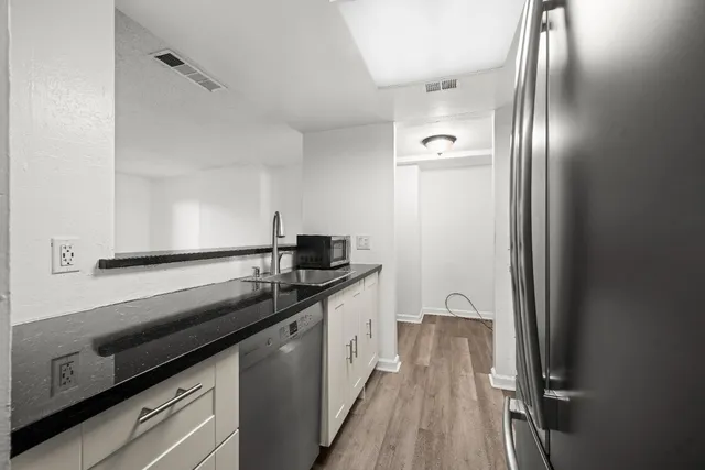 a kitchen with granite countertop stainless steel appliances a sink stove and refrigerator