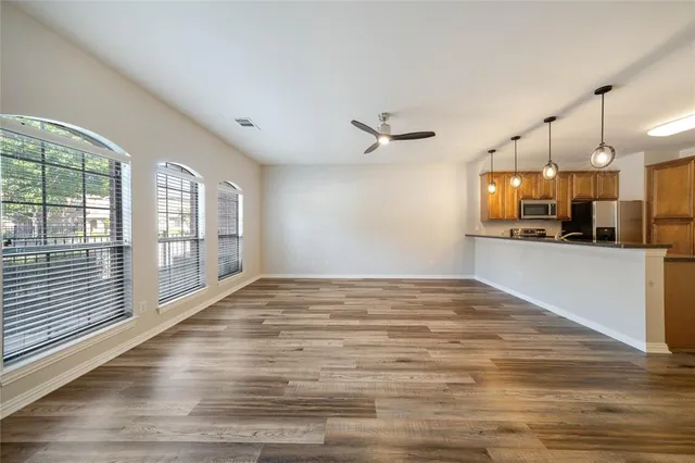 a view of a kitchen and an empty room with wooden floor and windows
