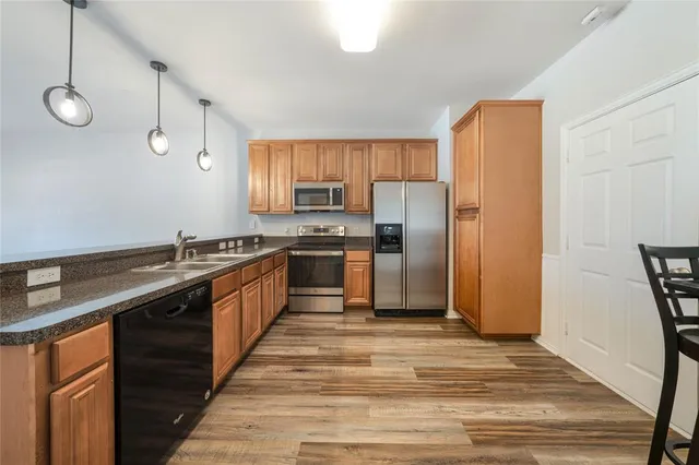 a large kitchen with cabinets wooden floor and stainless steel appliances