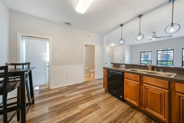 a large kitchen with a sink and dishwasher a stove top oven with wooden floor