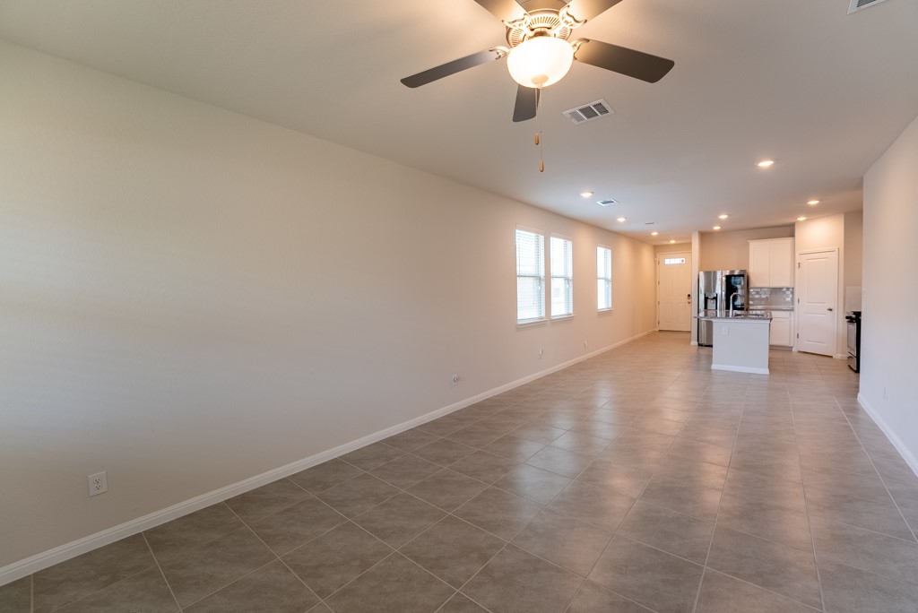 6310 Wolf Pack Drive Pflugerville, TX 78660 - Photo 14 of 34 an empty room with wooden floor fan and windows