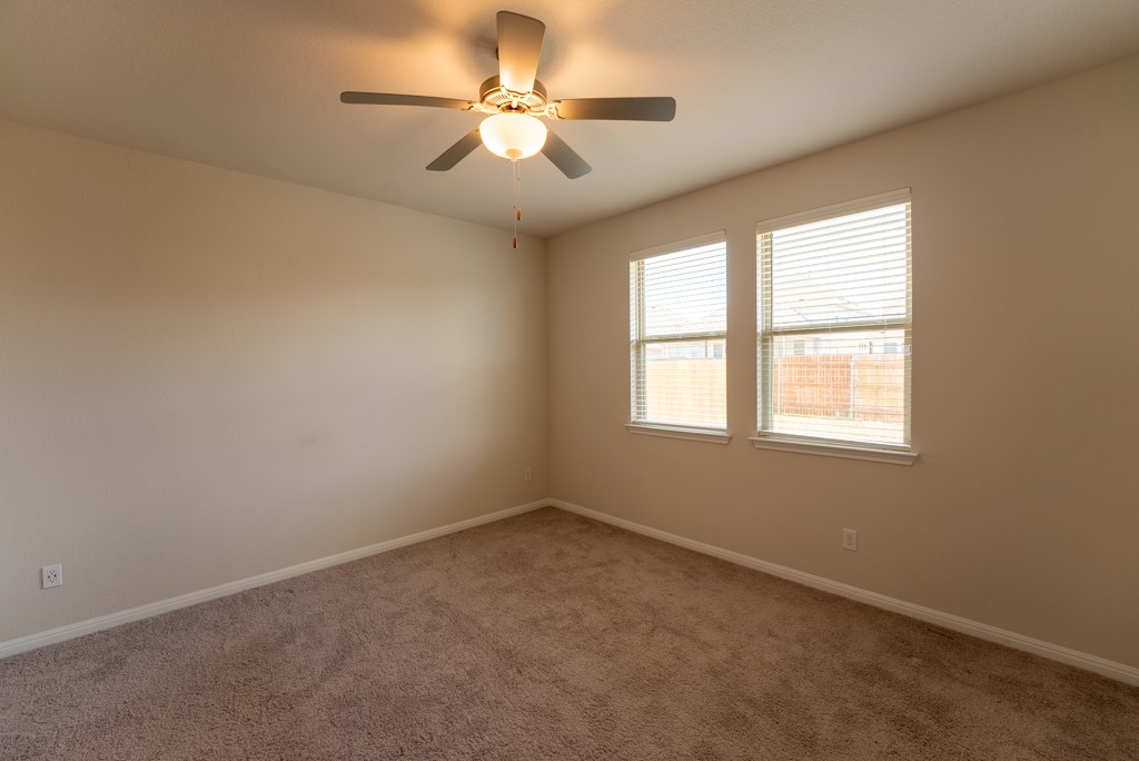 6310 Wolf Pack Drive Pflugerville, TX 78660 - Photo 15 of 33 an empty room with a chandelier fan and windows