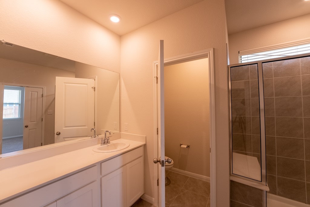 6310 Wolf Pack Drive Pflugerville, TX 78660 - Photo 19 of 34 a bathroom with a shower sink vanity and mirror