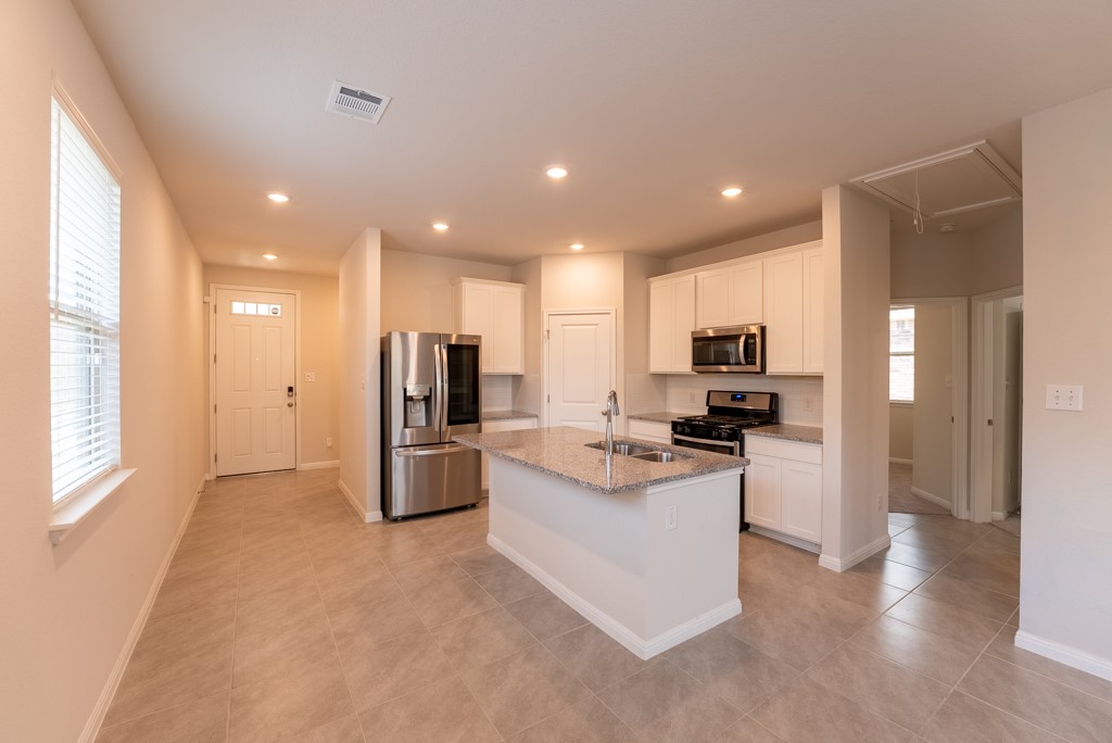 6310 Wolf Pack Drive Pflugerville, TX 78660 - Photo 6 of 34 a kitchen with stainless steel appliances kitchen island sink refrigerator and microwave