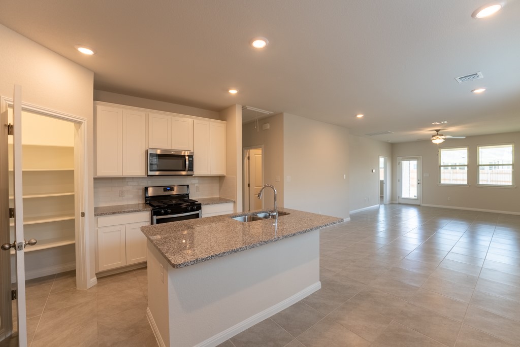 6310 Wolf Pack Drive Pflugerville, TX 78660 - Photo 9 of 34 a kitchen with stainless steel appliances a sink stove and refrigerator