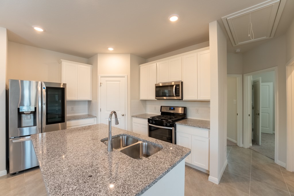 6310 Wolf Pack Drive Pflugerville, TX 78660 - Photo 10 of 34 a kitchen with stainless steel appliances granite countertop a sink and a refrigerator