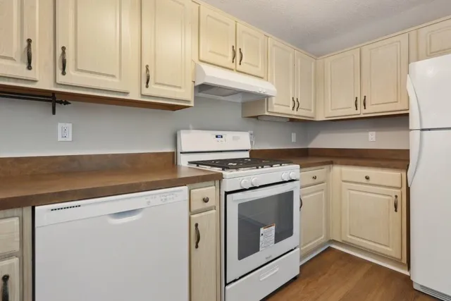 a kitchen with granite countertop white cabinets and white appliances