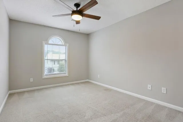 an empty room with a window and a fan