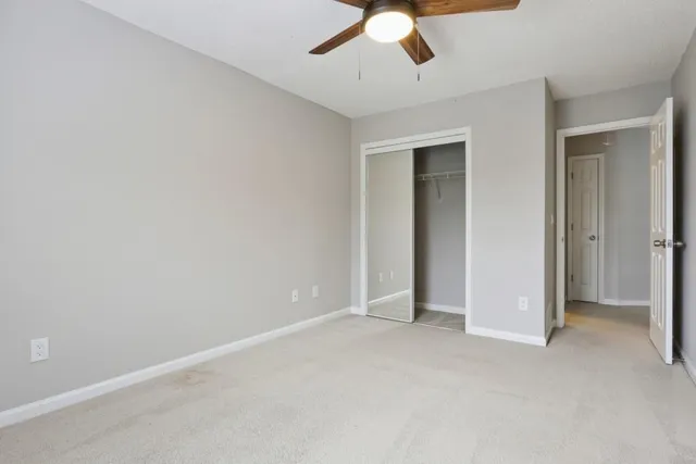 an empty room with a ceiling fan and carpet