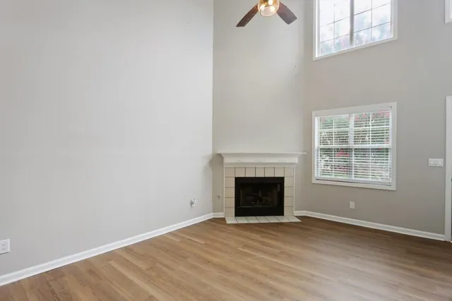 an empty room with wooden floor fireplace and windows