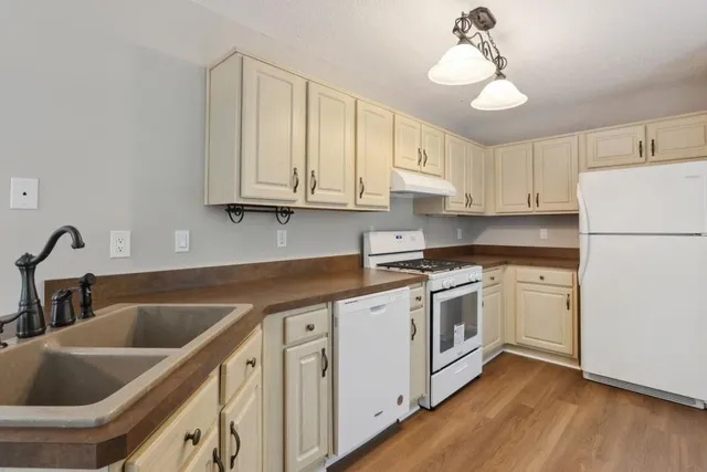 a kitchen with granite countertop white cabinets and white appliances