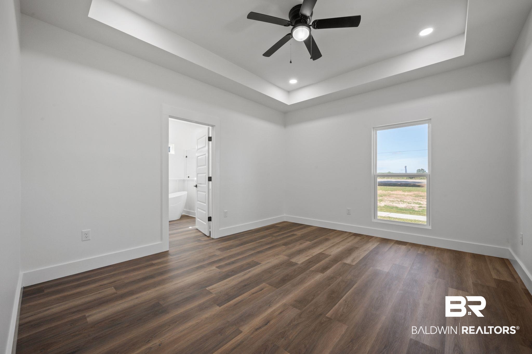 12100 Lott Road Chunchula, AL 36521 - Photo 8 of 21 Empty room with ceiling fan, a raised ceiling, and hardwood / wood-style floors