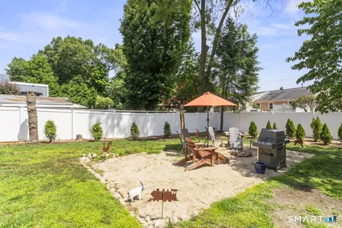 a view of backyard with seating space and trees in the background