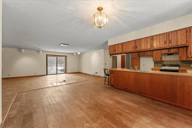 a kitchen with stainless steel appliances kitchen island granite countertop a sink refrigerator stove and wooden cabinets