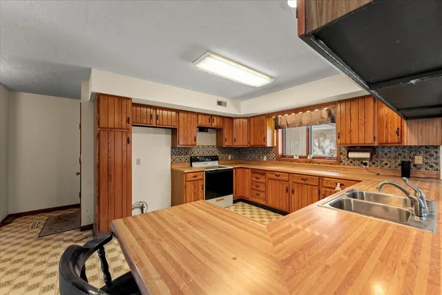 a kitchen with a stove a sink dishwasher a refrigerator and wooden cabinets