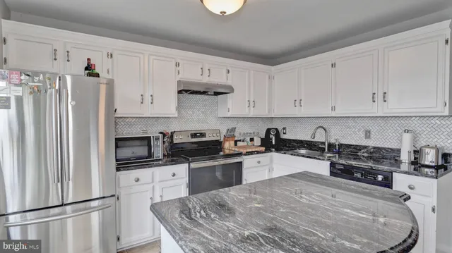 a kitchen with stainless steel appliances granite countertop a refrigerator sink and white cabinets