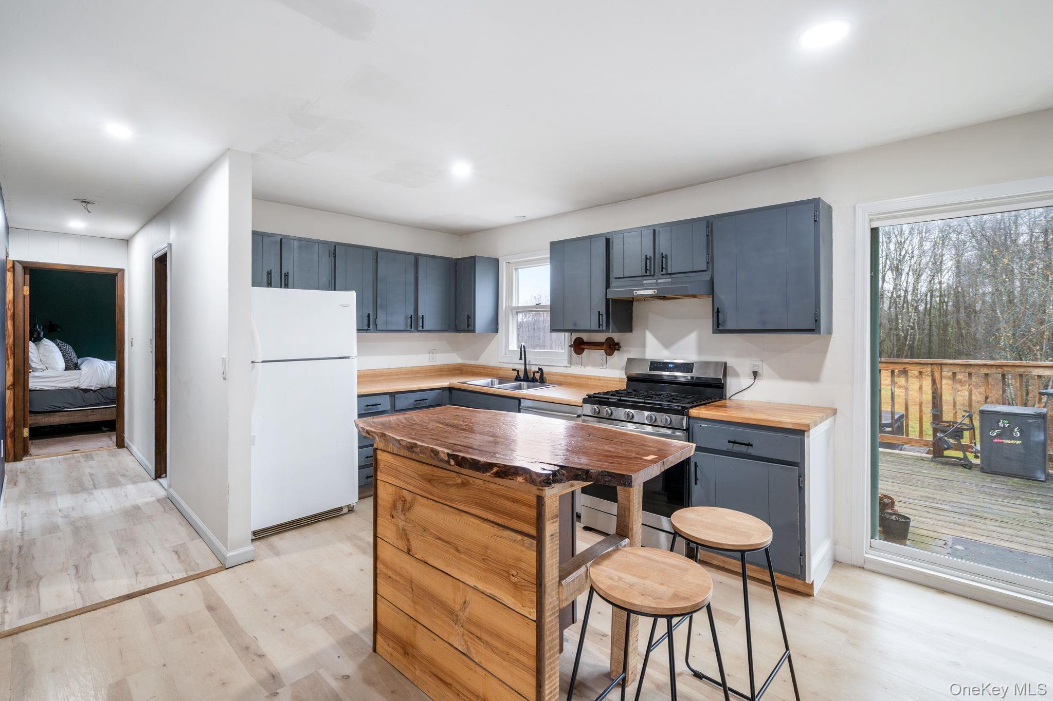 178 Bowers Road Loch Sheldrake, NY 12759 - Photo 11 of 47 a kitchen with stainless steel appliances granite countertop a stove a refrigerator a sink a dining table and chairs with wooden floor