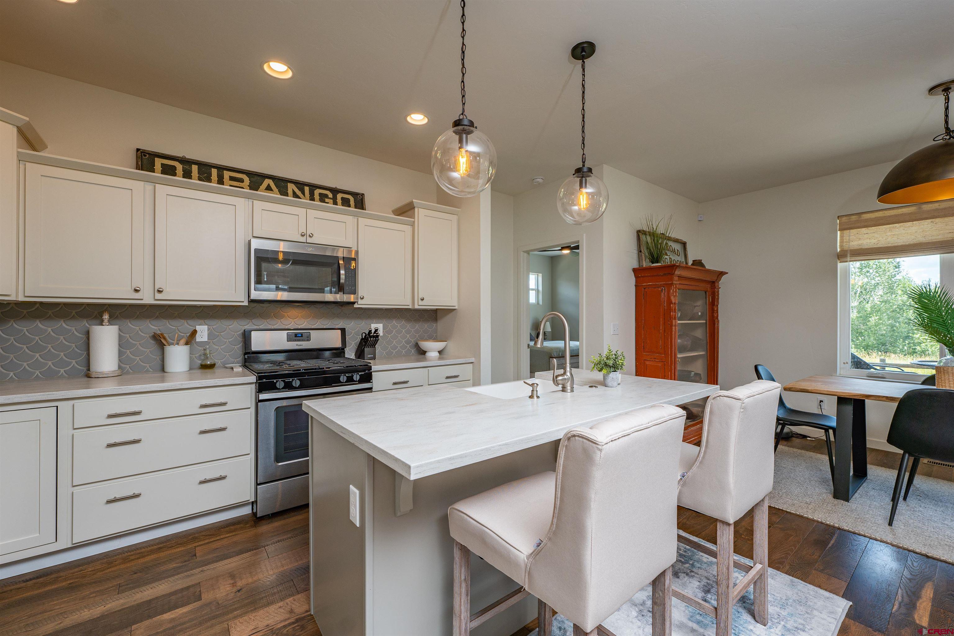 74 Prospector Avenue Durango, CO 81301 - Photo 6 of 30 a open kitchen with stainless steel appliances granite countertop a stove top oven a refrigerator a sink dishwasher a dining table and chairs with wooden floor