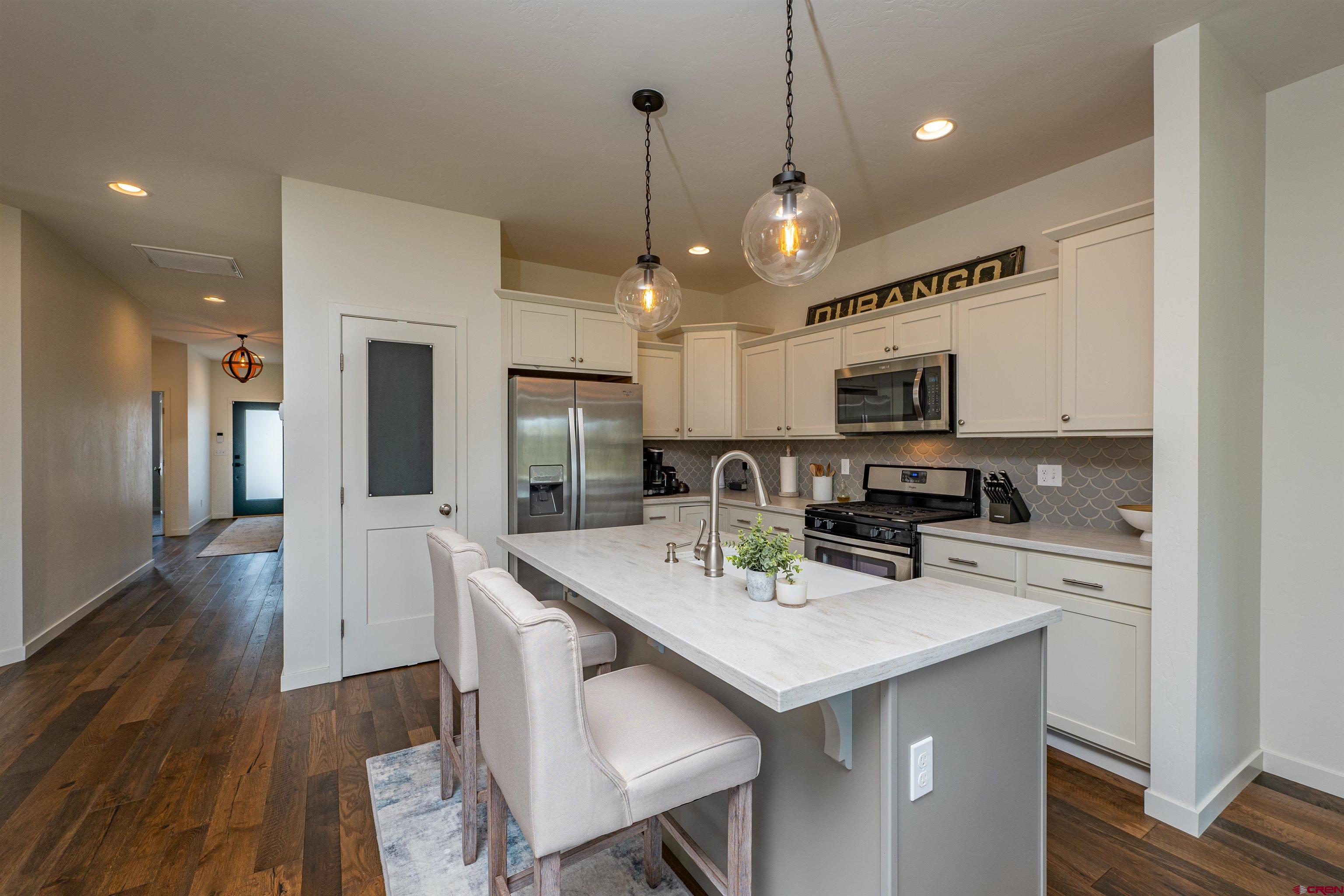 74 Prospector Avenue Durango, CO 81301 - Photo 7 of 30 a kitchen with stainless steel appliances granite countertop a sink a stove a refrigerator cabinets and chairs