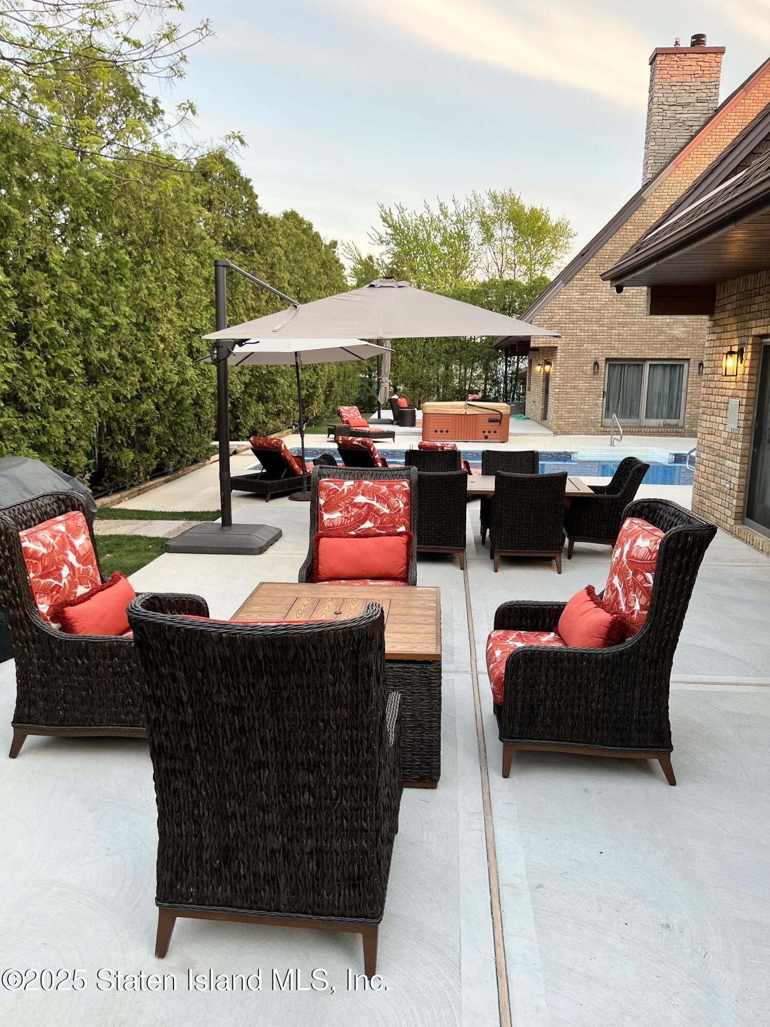 Undisclosed Address Staten Island, NY 10307 - Photo 59 of 72 a view of a patio with couches table and chairs under an umbrella with a fire pit