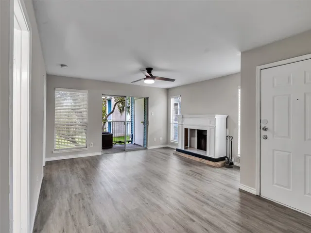 an empty room with wooden floor fireplace and windows