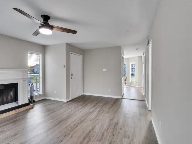 a view of an empty room with wooden floor fireplace and a window