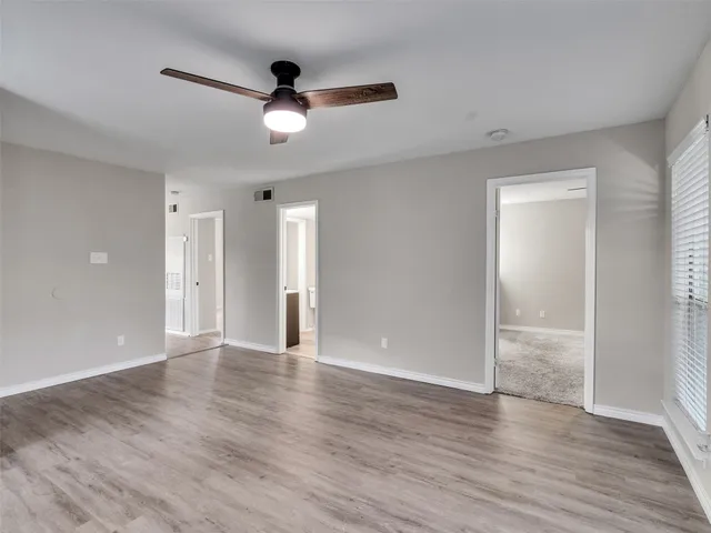 an empty room with wooden floor and a ceiling fan
