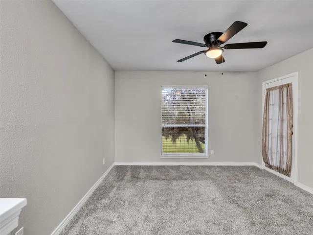 an empty room with windows and ceiling fan