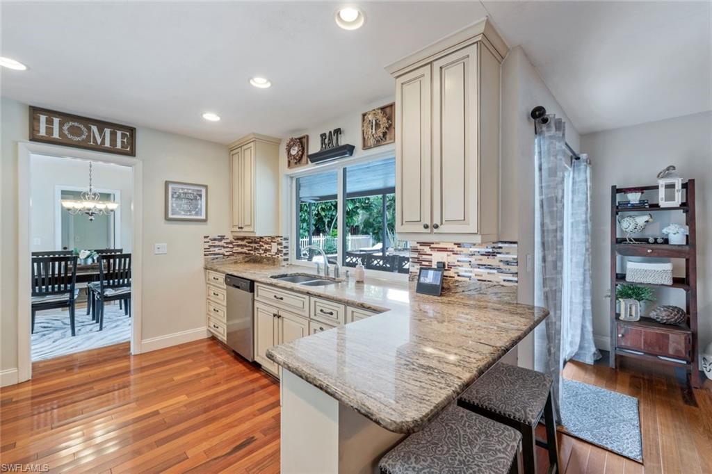 289 Burning Tree Drive Naples, FL 34105 - Photo 11 of 36 a kitchen with stainless steel appliances granite countertop a stove refrigerator and a dining table with wooden floor