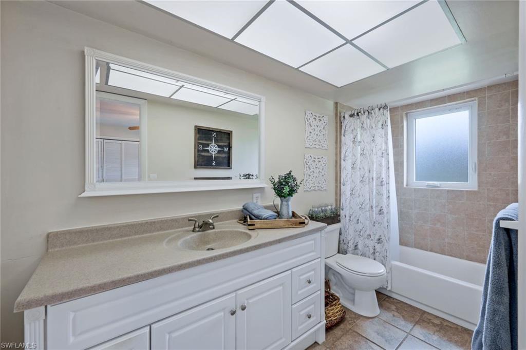 289 Burning Tree Drive Naples, FL 34105 - Photo 17 of 36 a bathroom with a granite countertop sink toilet a large mirror a bathtub and shower