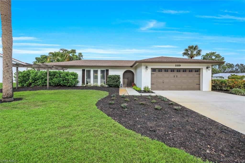 289 Burning Tree Drive Naples, FL 34105 - Photo 2 of 36 a front view of a house with garden