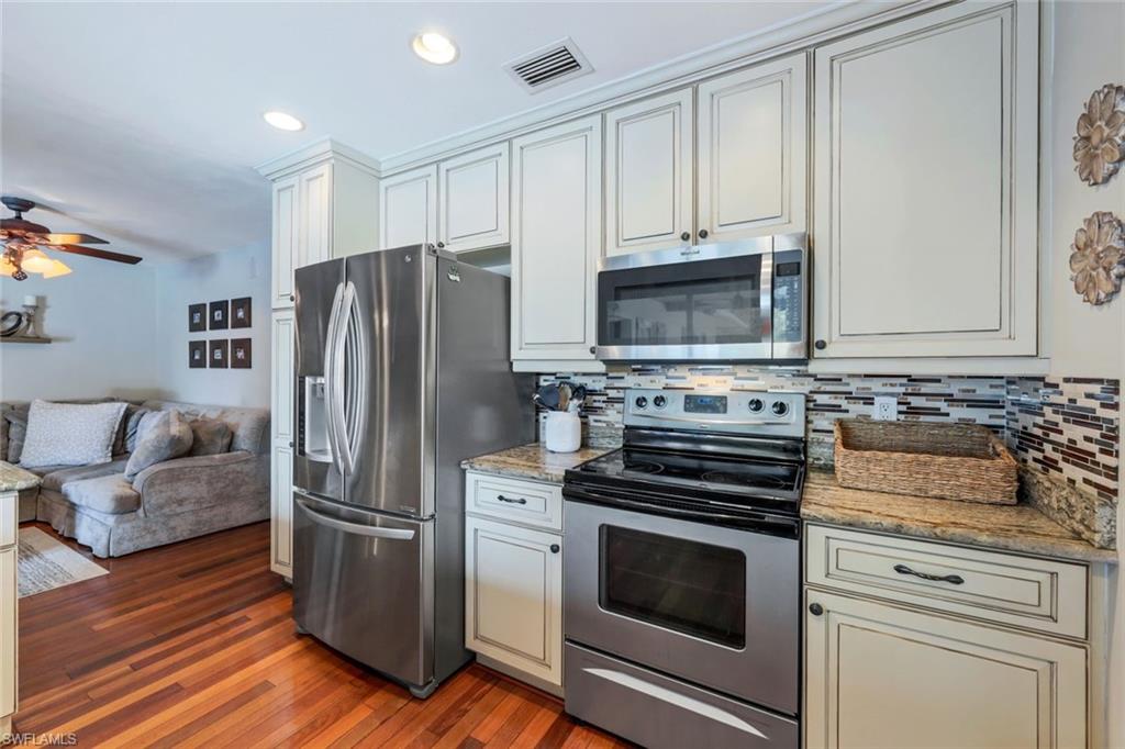 289 Burning Tree Drive Naples, FL 34105 - Photo 10 of 36 a kitchen with granite countertop a refrigerator stove and microwave